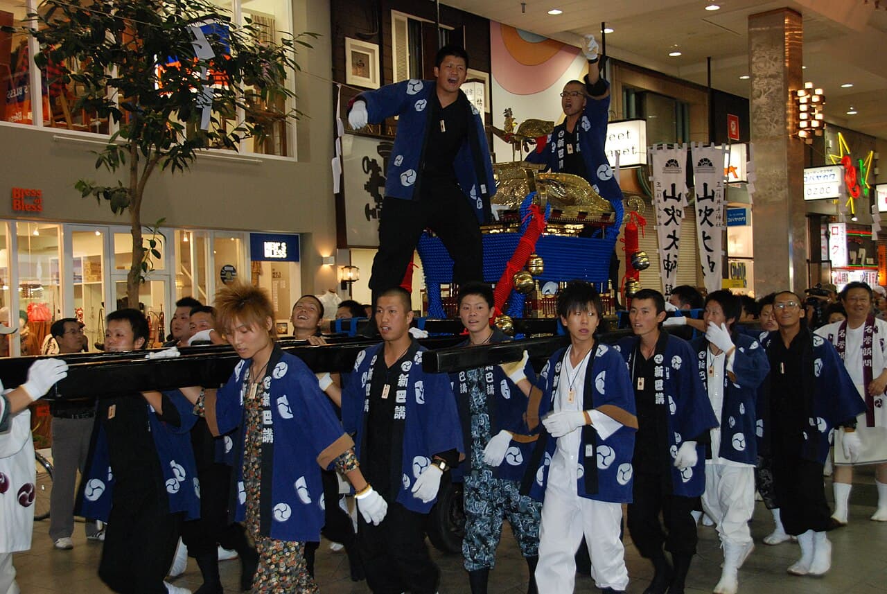 Festival participants shouldering and carrying a mikoshi portable shrine through the street