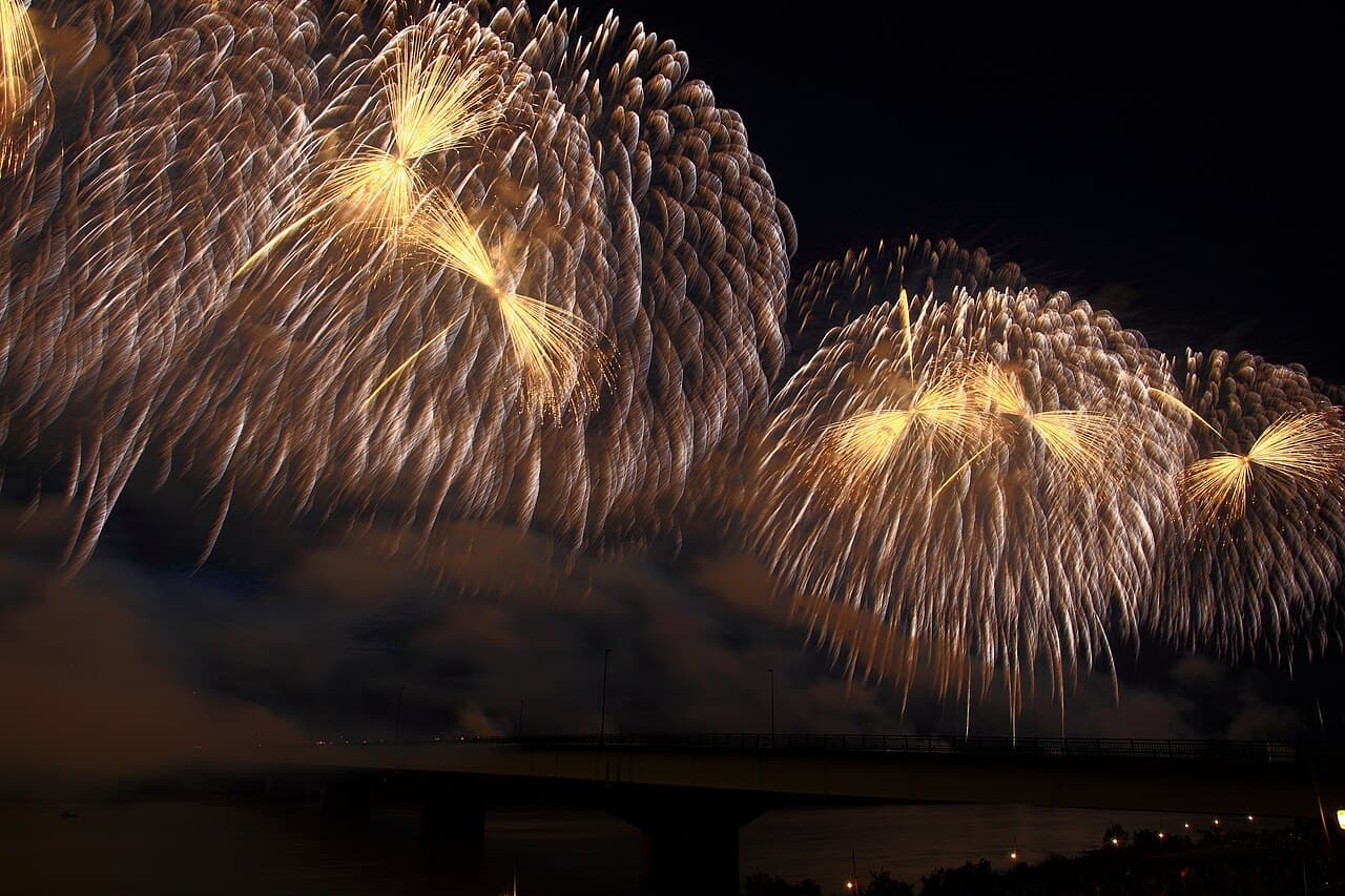 Wide 'Phoenix' fireworks shells lighting the night sky over the Shinano River at the Nagaoka Festival