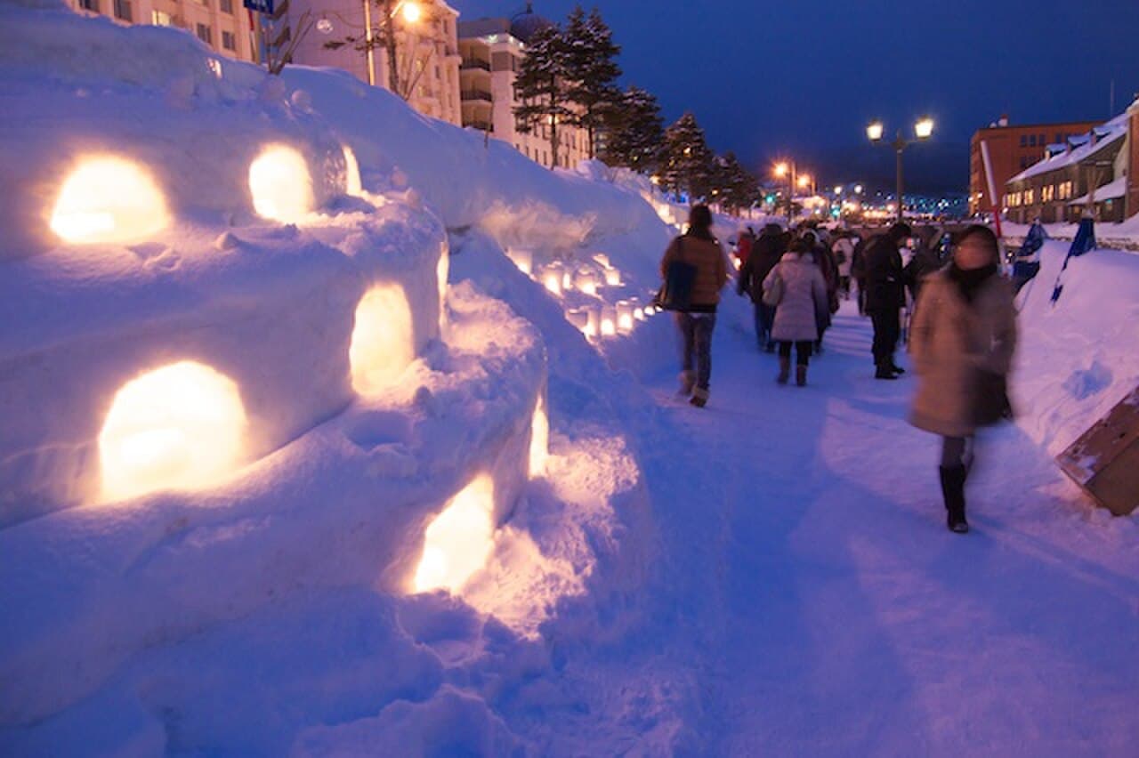 Snow lanterns glowing along a canal during the Otaru Snow Light Path Festival