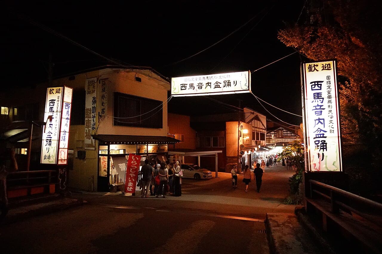 A masked dancer in a black hikosa-zukin hood and indigo kimono dancing at Nishimonai Bon Odori, Akita