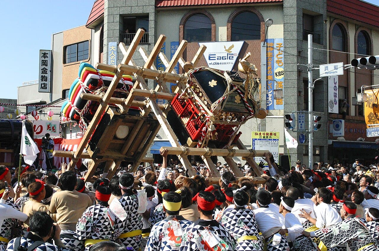 The Imari Tonten-ton clash at the Hamamachi crossing: a mikoshi and a danjiri float locked together and hoisted above bearers in happi coats (photo 2002)